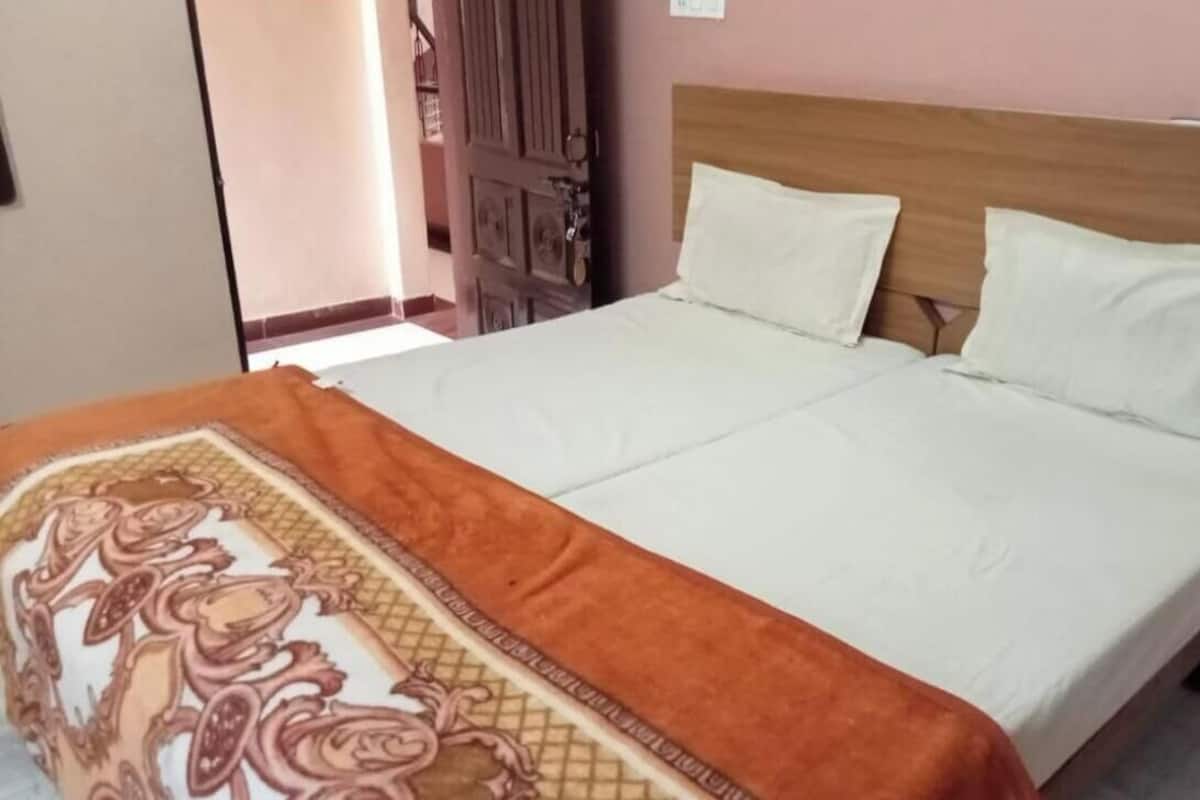 A bed with a wooden headboard, white bedding, and a patterned throw blanket.