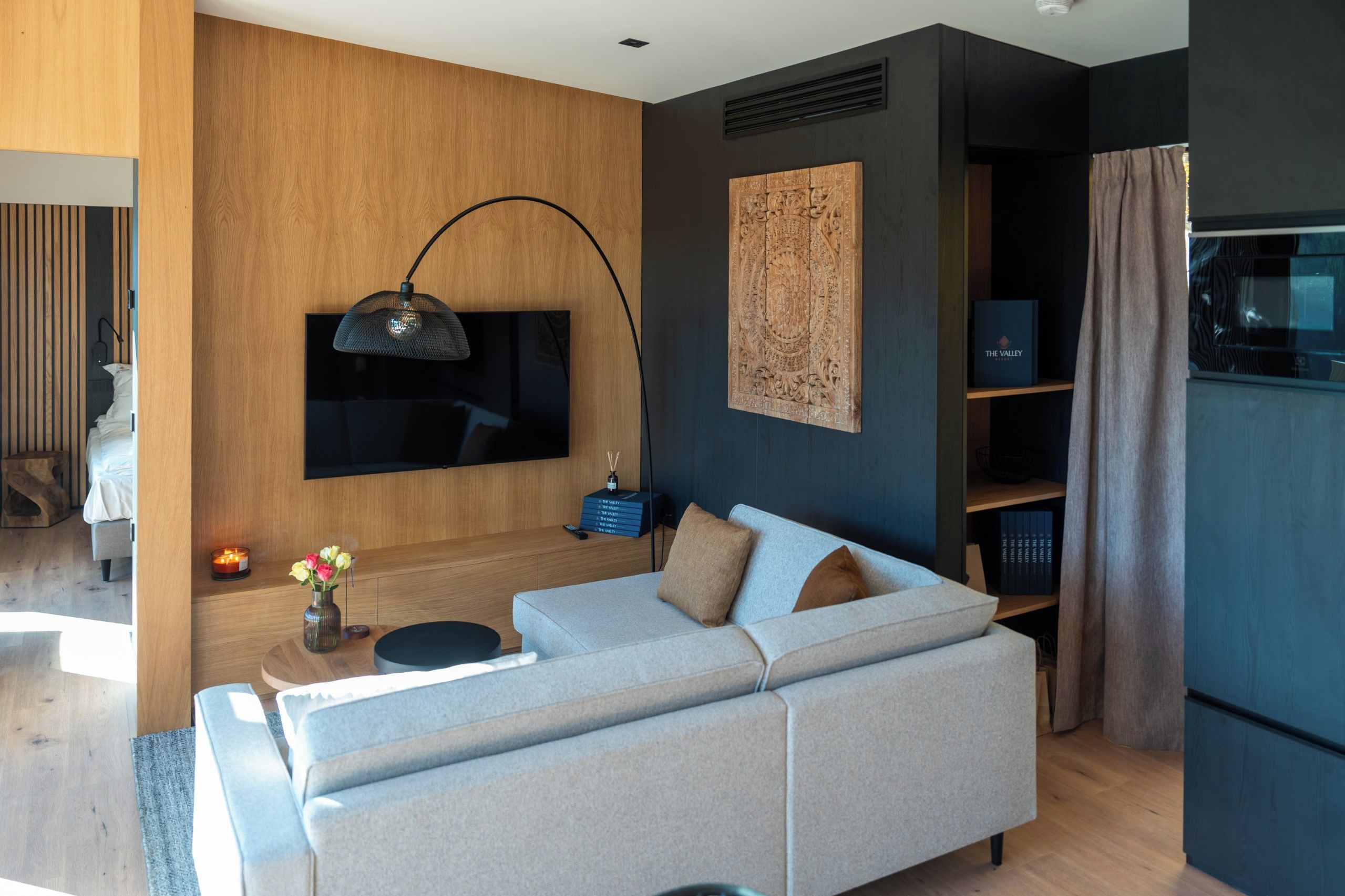 Una sala moderna con un sofá, un televisor montado en la pared y una estantería.