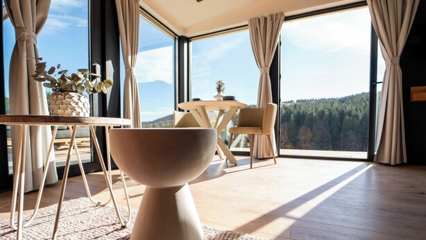 A modern room with a large window, a round table, a chair, and a decorative bowl. - The Valley Resort (Vama Buzăului)