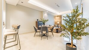 A modern dining area with a high ceiling, a central dining table, and a potted plant. - Spacious High-Floor 2BR with Stunning City and Burj Khalifa Views (Dubai)