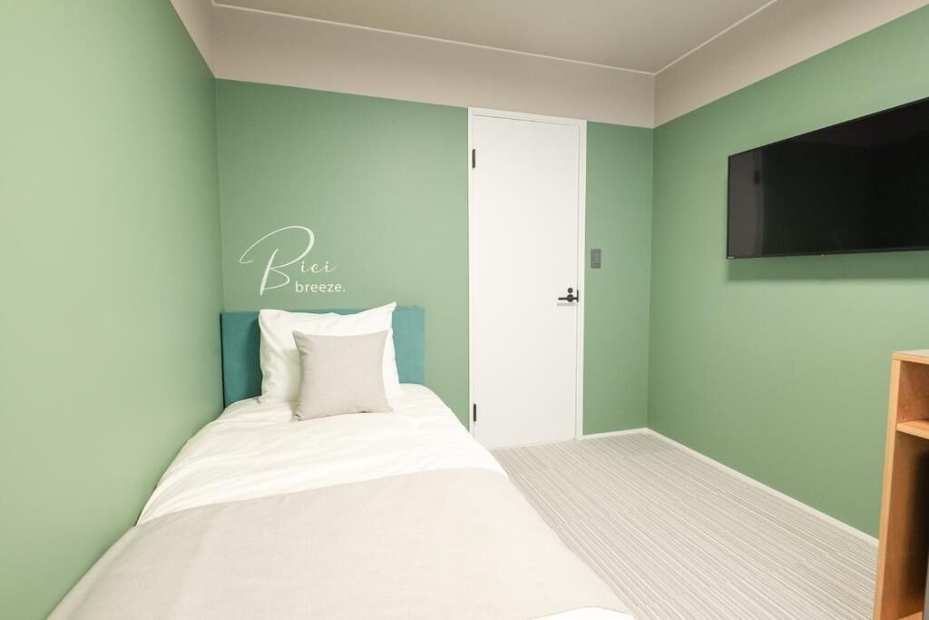 A bedroom with a bed, a door, and a TV on the wall.