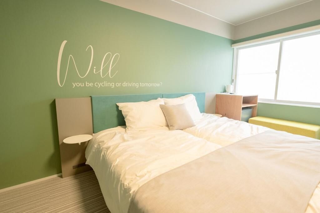 A bedroom with a bed, a bedside table, a nightstand, and a window.