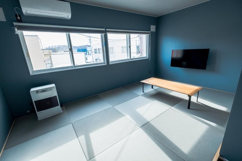 A room with a large window, a bench, and a wall-mounted TV.