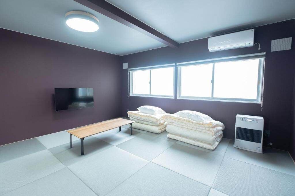 Een kamer met een bed, een bankje, een televisie en een raam.
