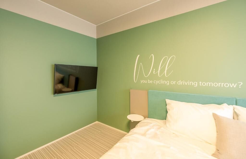 A bedroom with a bed, a wall-mounted TV, and a motivational quote.