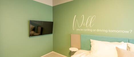 A bedroom with a bed, a wall-mounted TV, and a motivational quote.