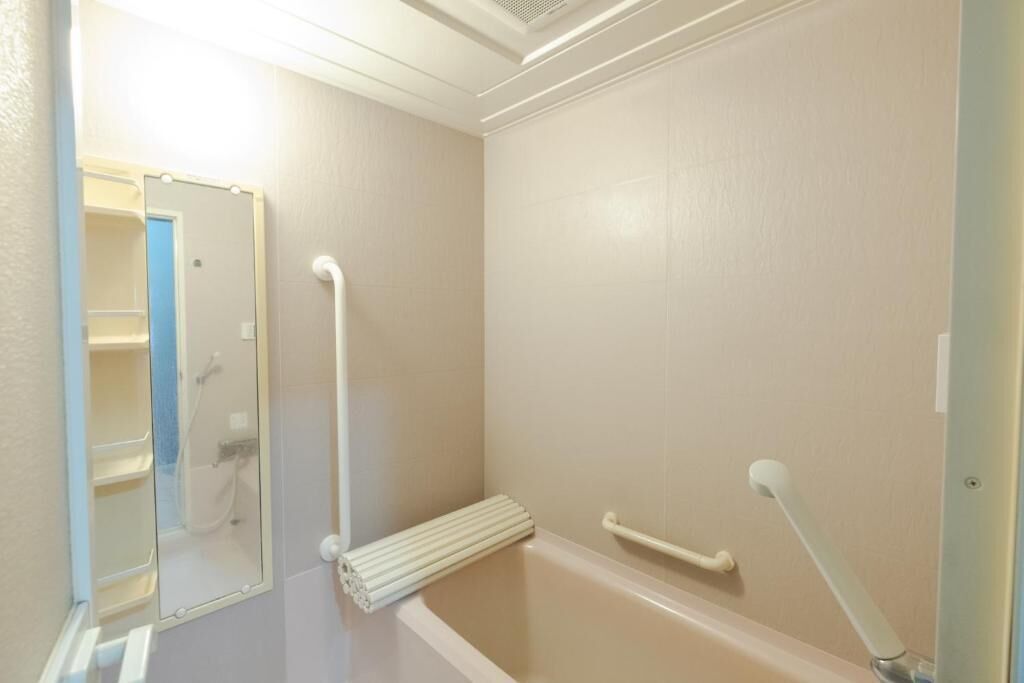 A bathroom with a bathtub, a shower, and a handrail.