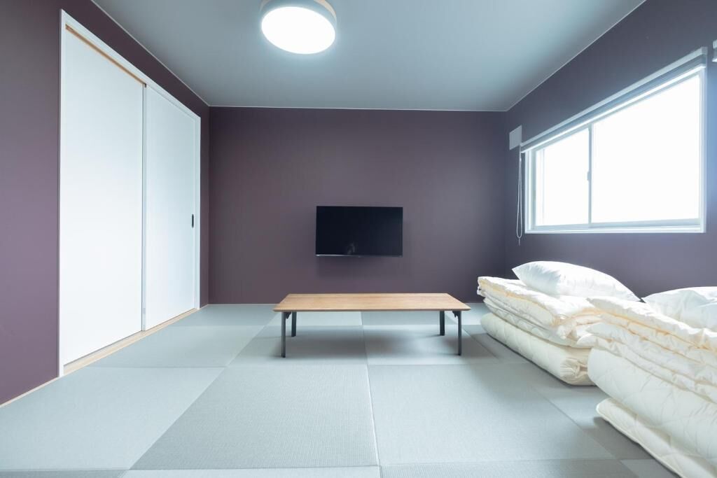 A room with a bed, a bench, a TV, and a wardrobe.