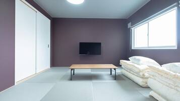 A room with a bed, a bench, a TV, and a wardrobe.