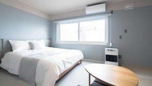 Ett modernt hotellrum med en säng, ett runt bord och ett fönster.