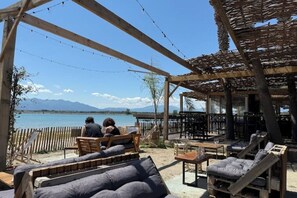 An outdoor seating area with wooden furniture and a view of a lake. - La Casita - A love story in the heart of the village (Villeneuve-de-la-Raho)
