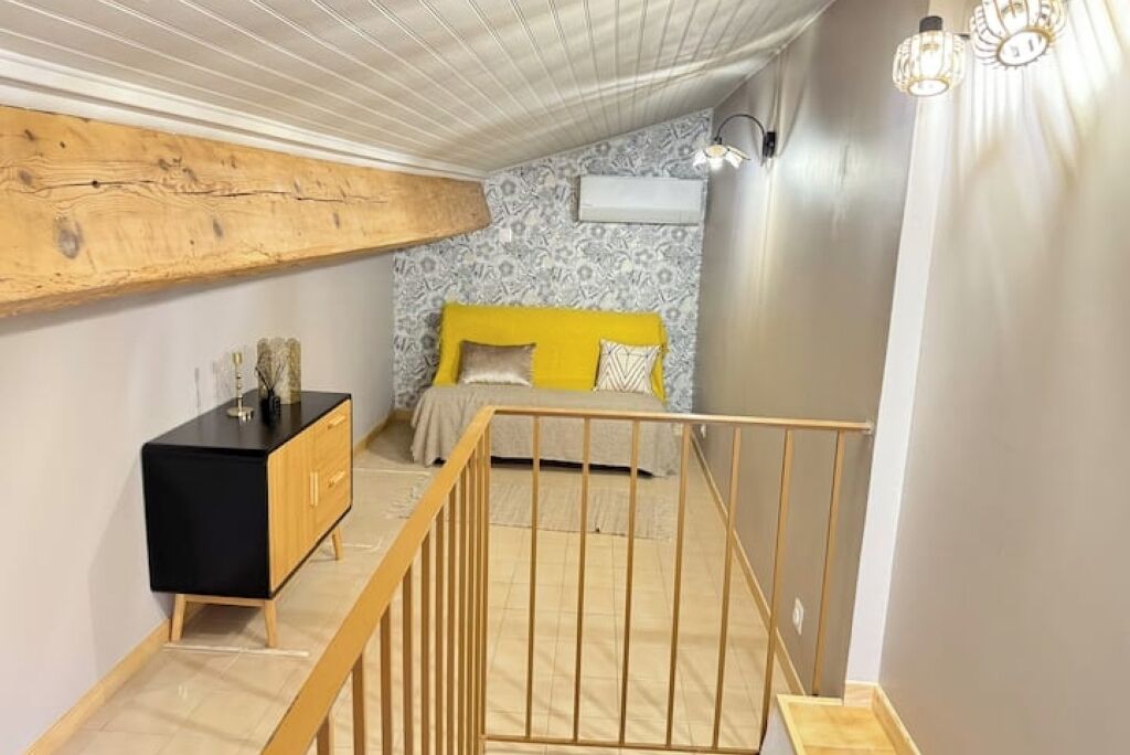 Una camera da letto con un letto giallo, una cassettiera nera e una panca in legno.