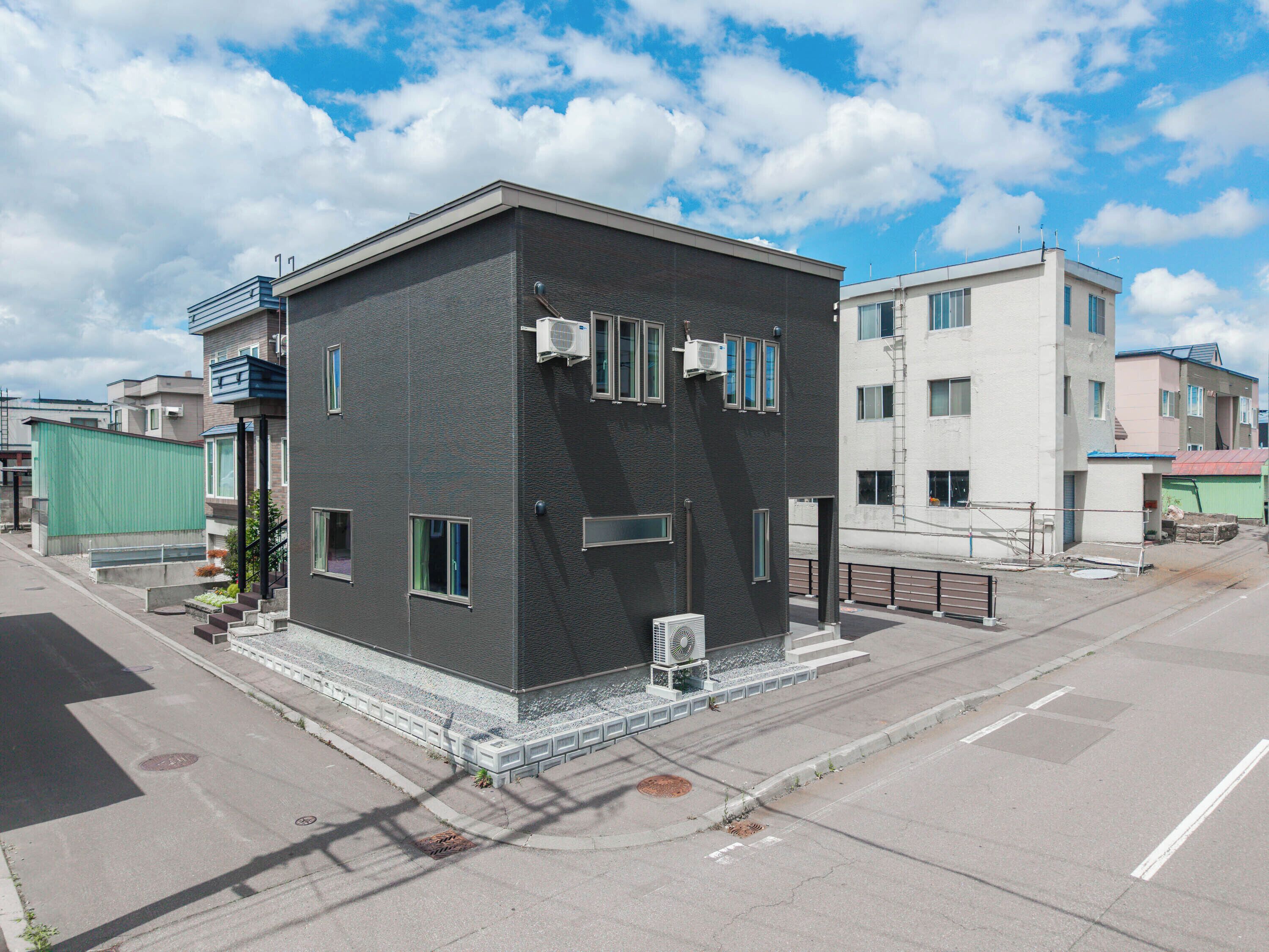 A modern two-story building with a flat roof, large windows, and a small balcony.