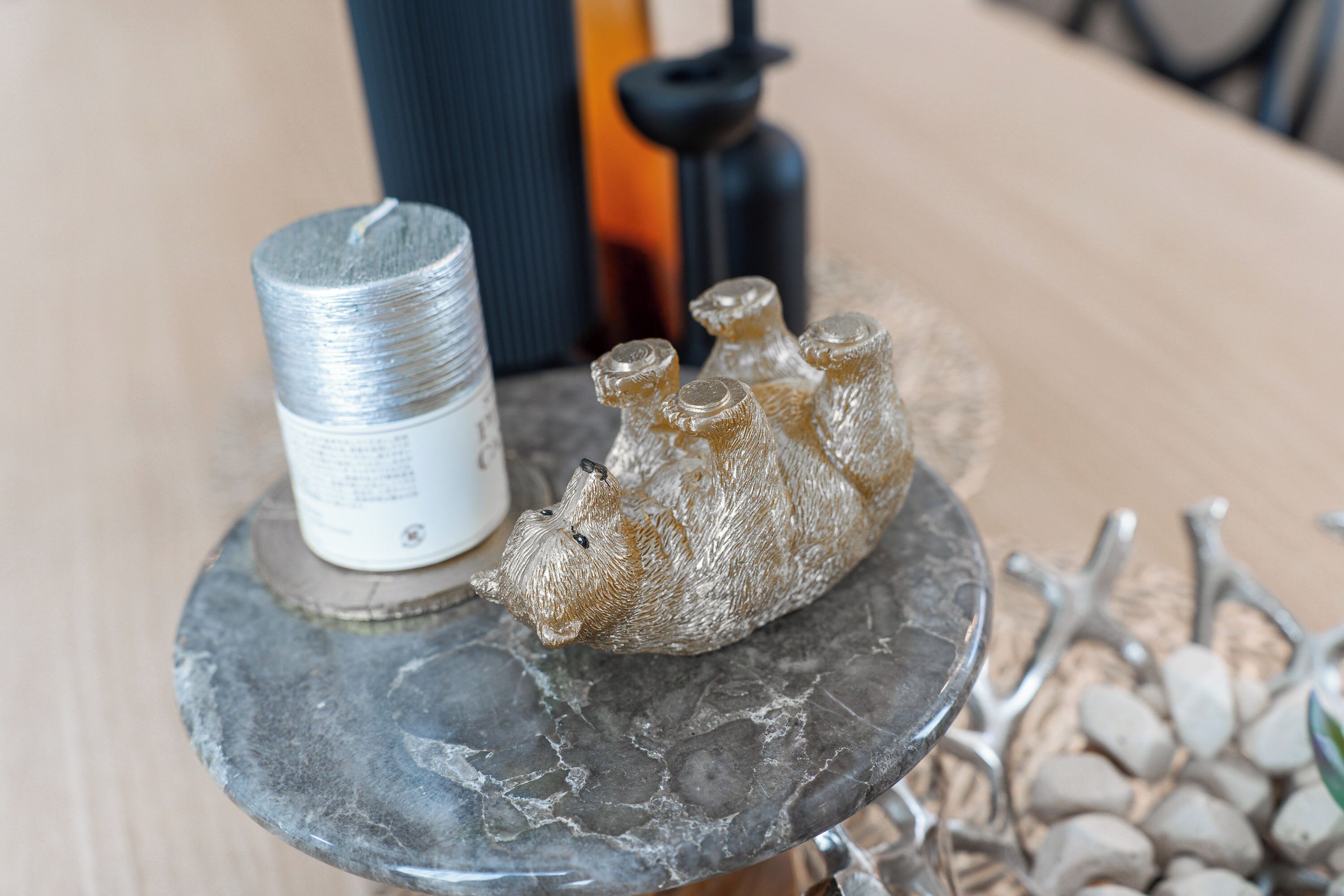 A 3D-printed sculpture on a marble table with a cylindrical container and a black object in the background.