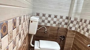 A bathroom with a toilet, a bidet, and a decorative ceramic pot. - White Ridge Hotel - Nagole (Hyderabad)