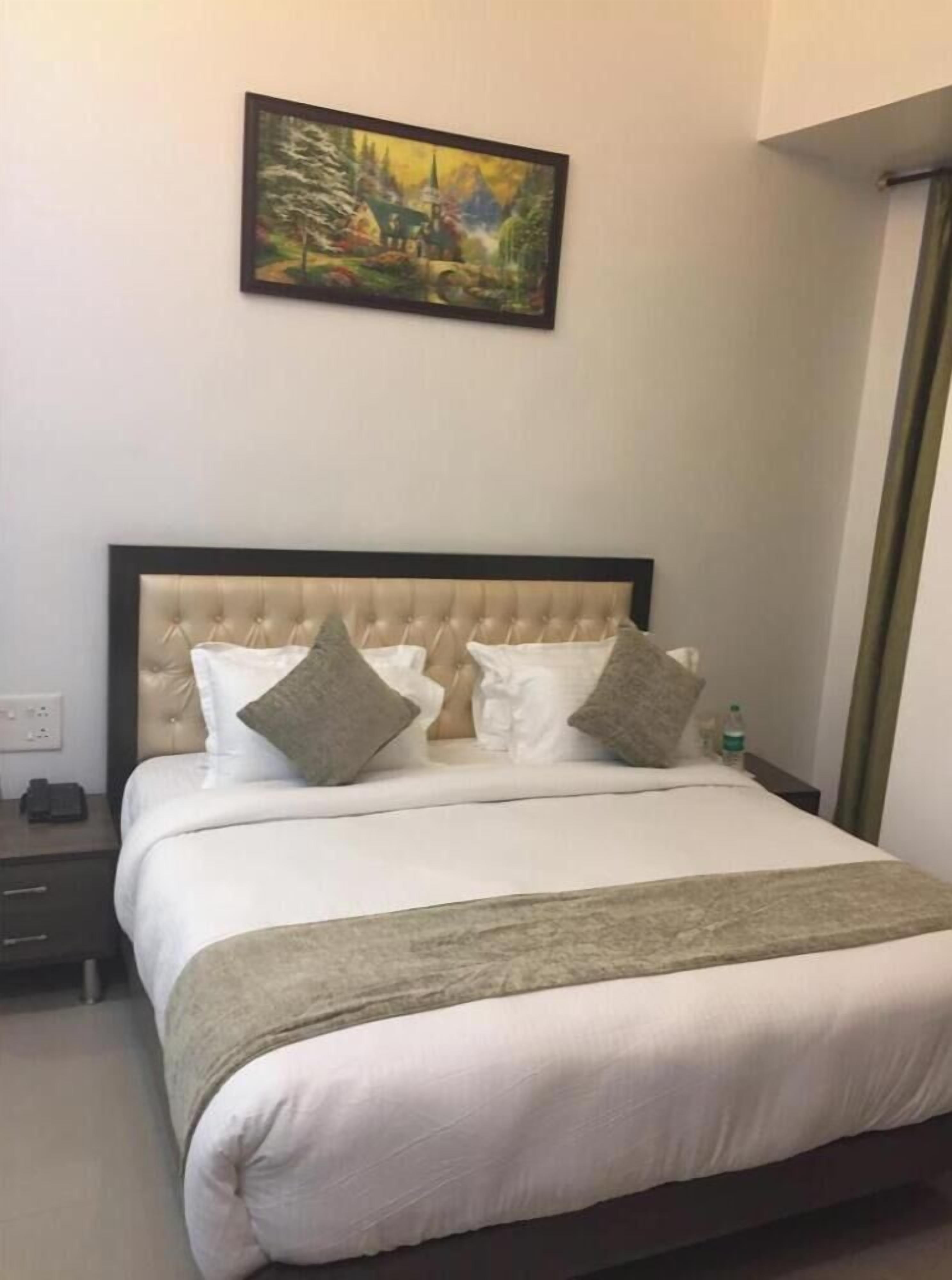 A neatly made bed with a tufted headboard, two pillows, and a blanket.