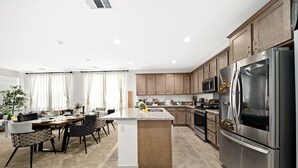 Een moderne keuken met een centraal eiland, roestvrijstalen apparatuur en houten kastjes.