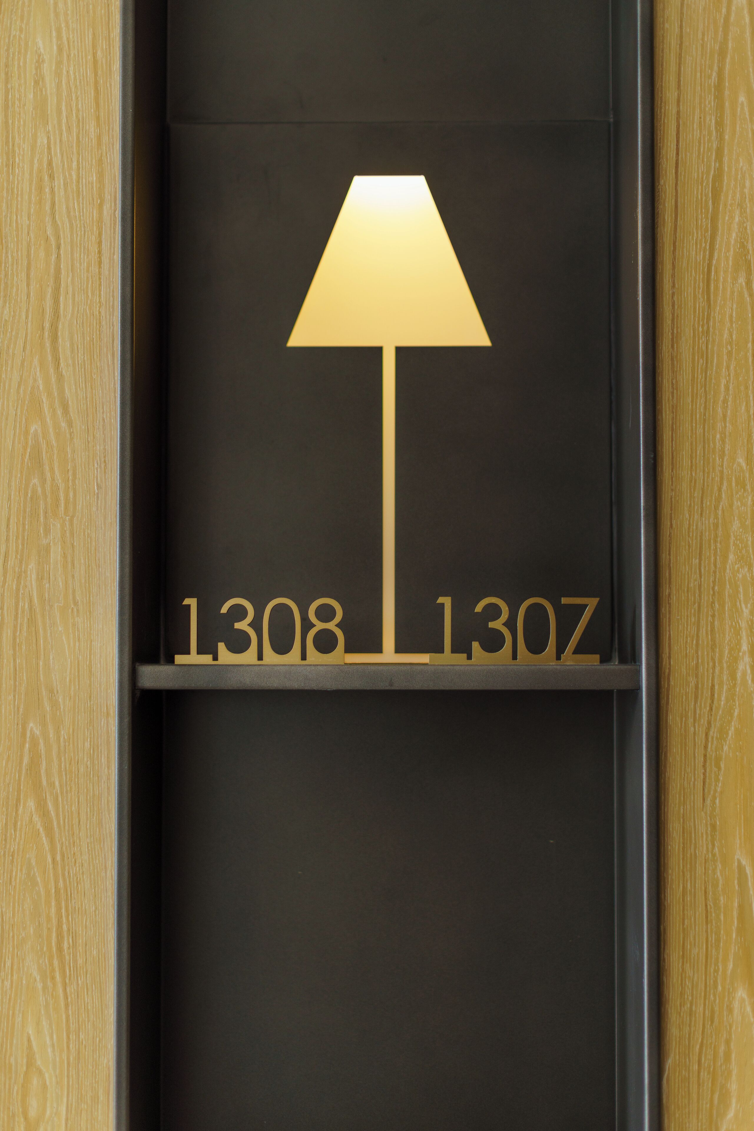 Een zwart schap met een gouden lamp en de cijfers 1308 en 130Z.