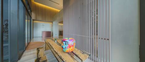 Un interior moderno con un banco de madera, una escultura esférica colorida y un panel de madera vertical.