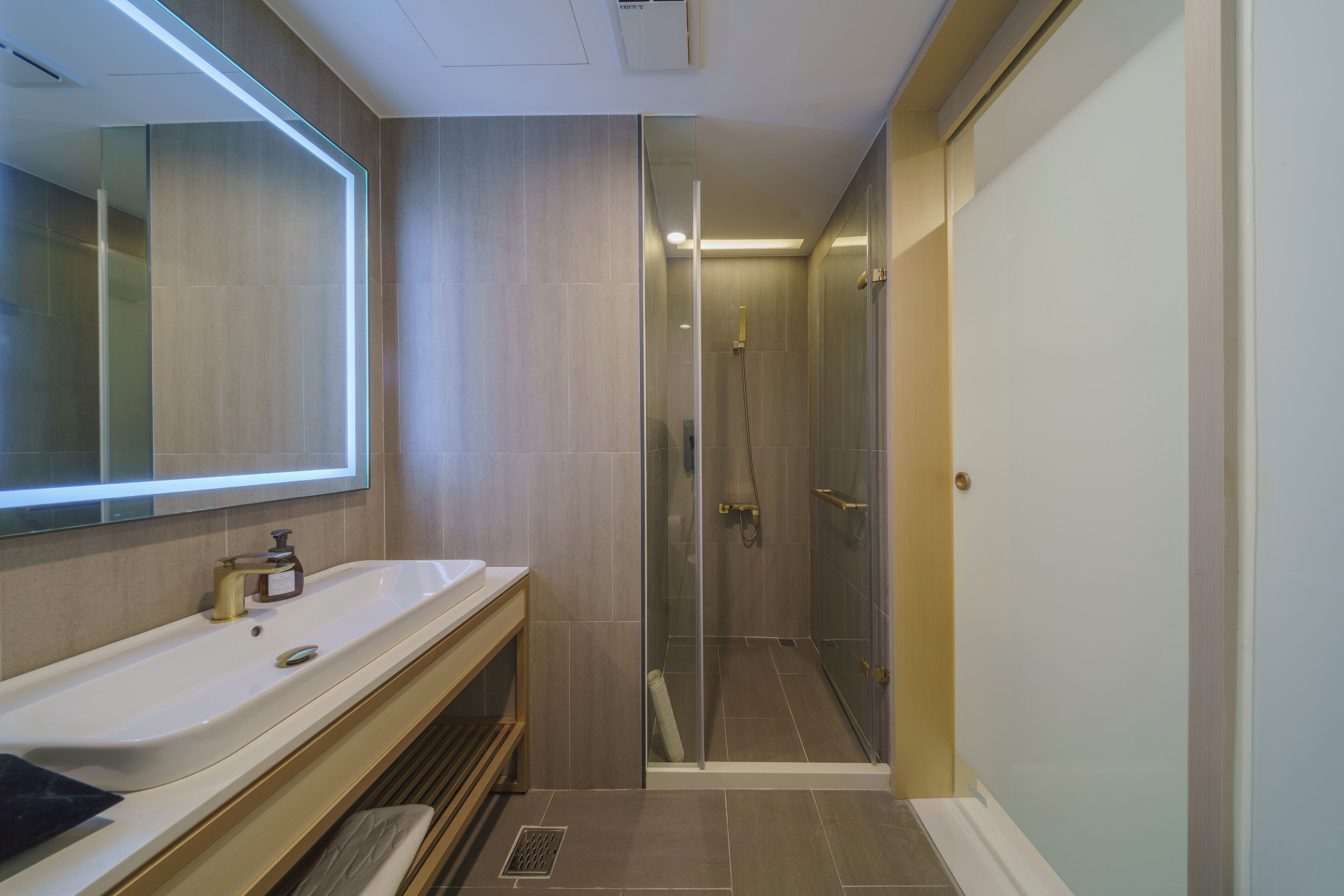 A modern bathroom with a glass-enclosed shower, a large mirror, and a vanity with a sink.