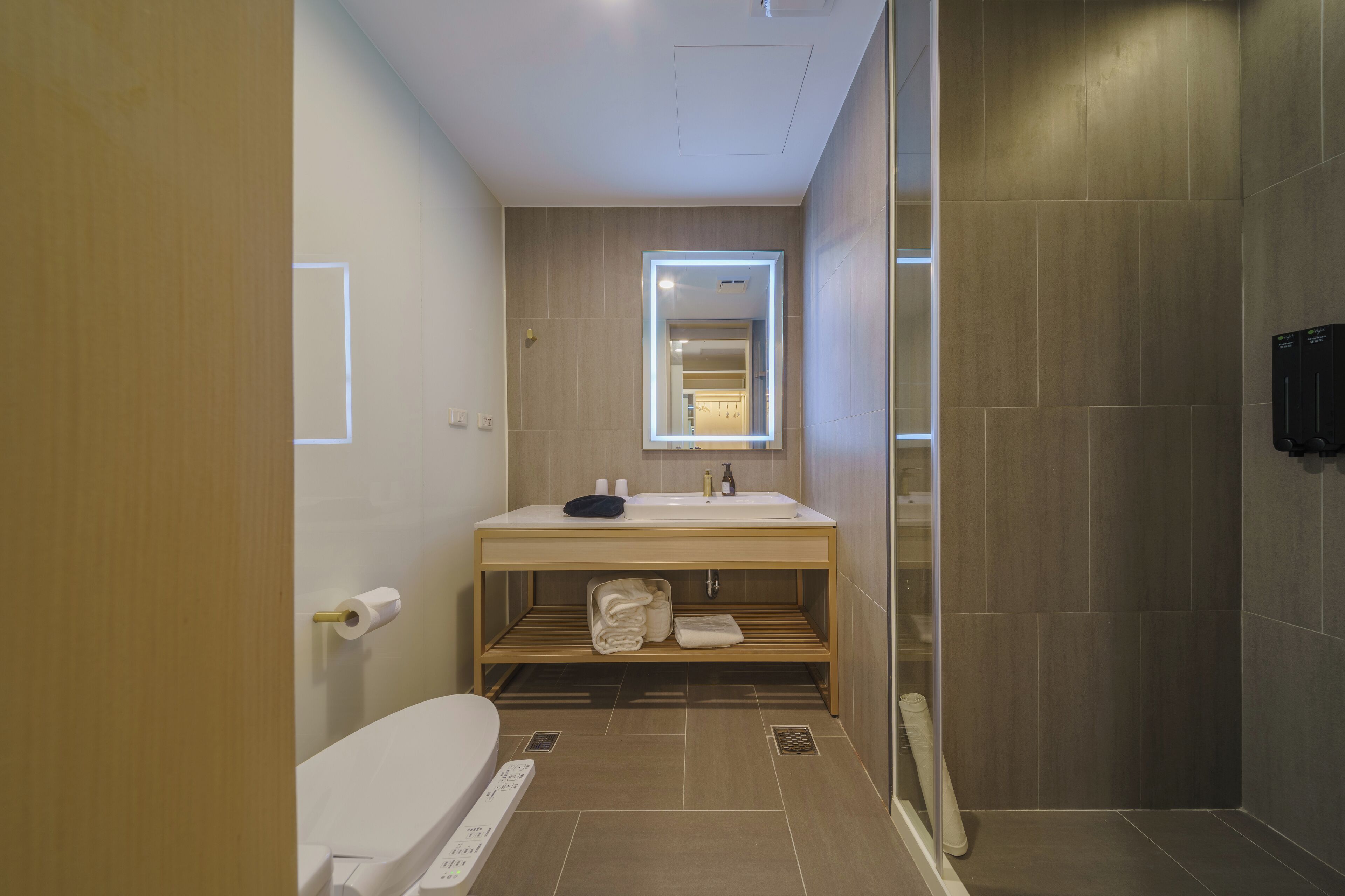 A modern bathroom with a wooden vanity, a toilet, and a shower area.