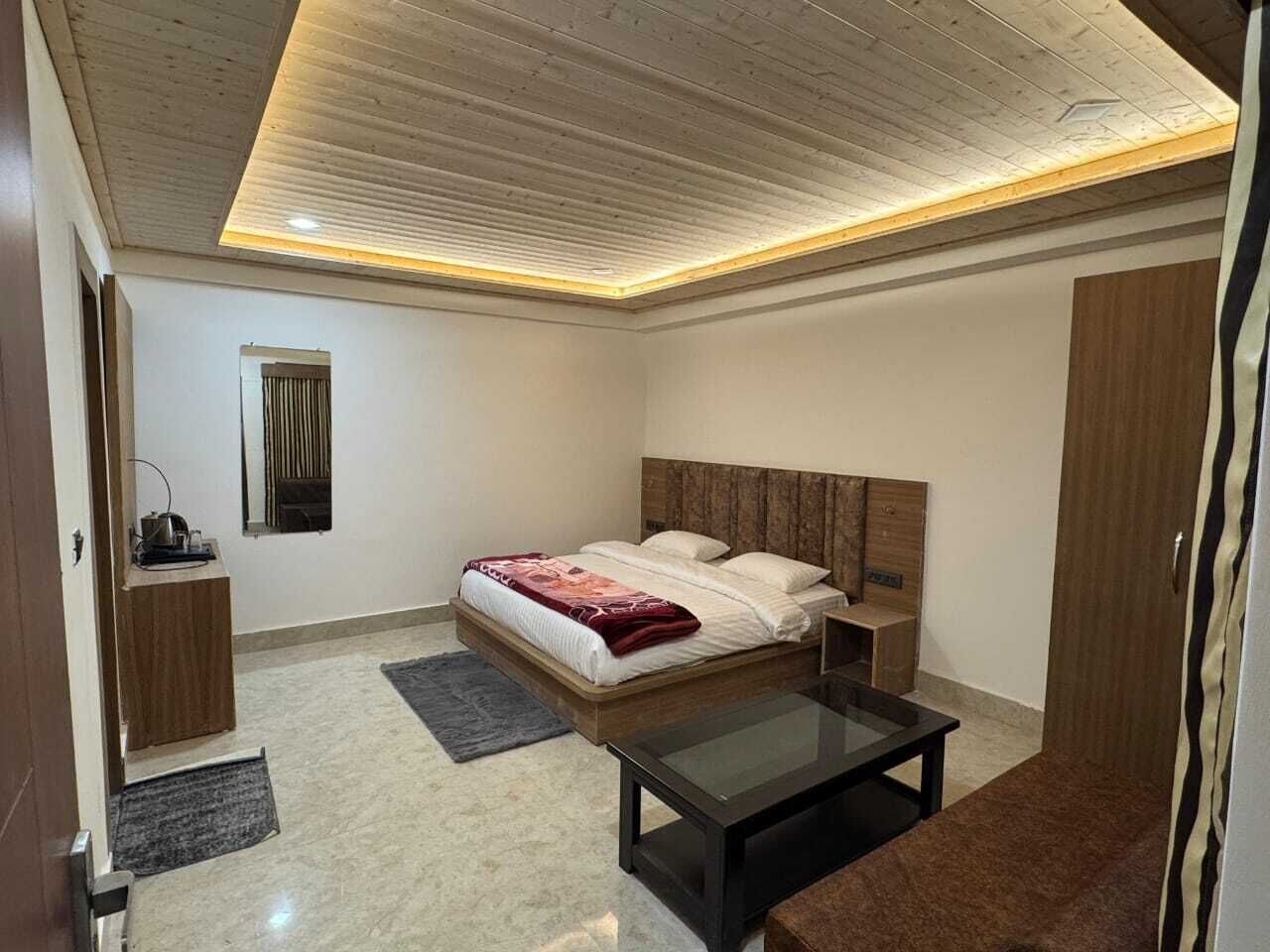 Ein modernes Schlafzimmer mit einem Holzkopfende, einem Glastisch und einem Nachttisch.