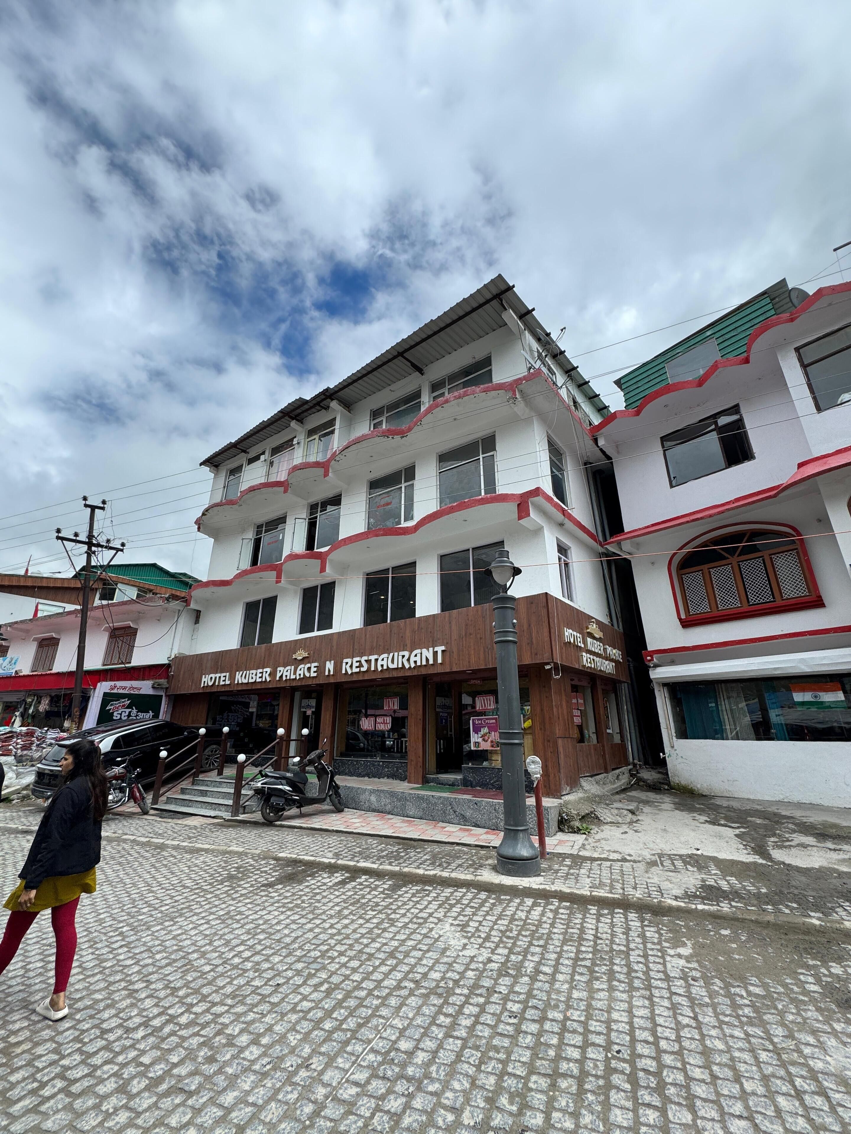 Un immeuble à plusieurs étages qui abrite un restaurant appelé « Hotel Kuber Palace N Restaurant » au rez-de-chaussée.