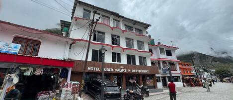 Un hotel con un letrero que dice "HOTEL KUBER PALACE N RESTAURANT" en la planta baja.