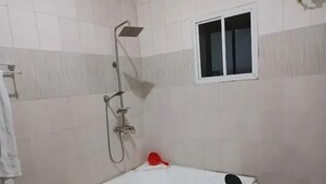 Ein Badezimmer mit einer weißen Badewanne, einer Duschbrause und einem kleinen Fenster.