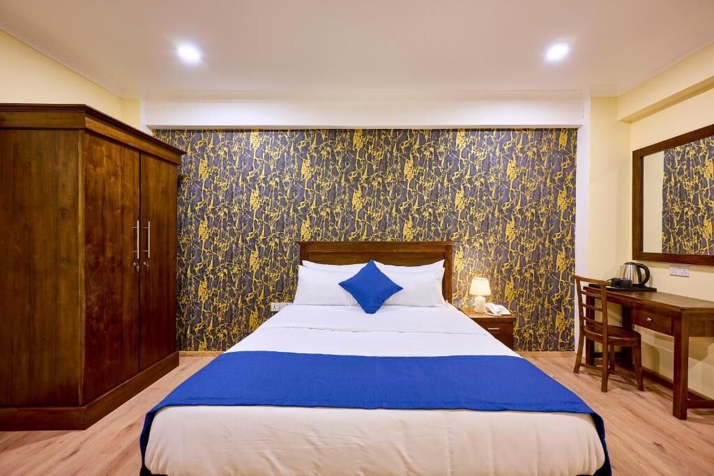 Una habitación de hotel con una cama grande, un armario de madera, un escritorio y un espejo.