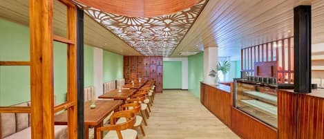 Un restaurante moderno con mobiliario de madera, techo curvo y un pasillo central.