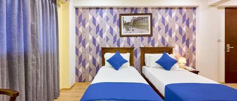 Habitación de hotel con dos camas, un ventanal con cortinas, un cuadro en la pared y un equipo de aire acondicionado.