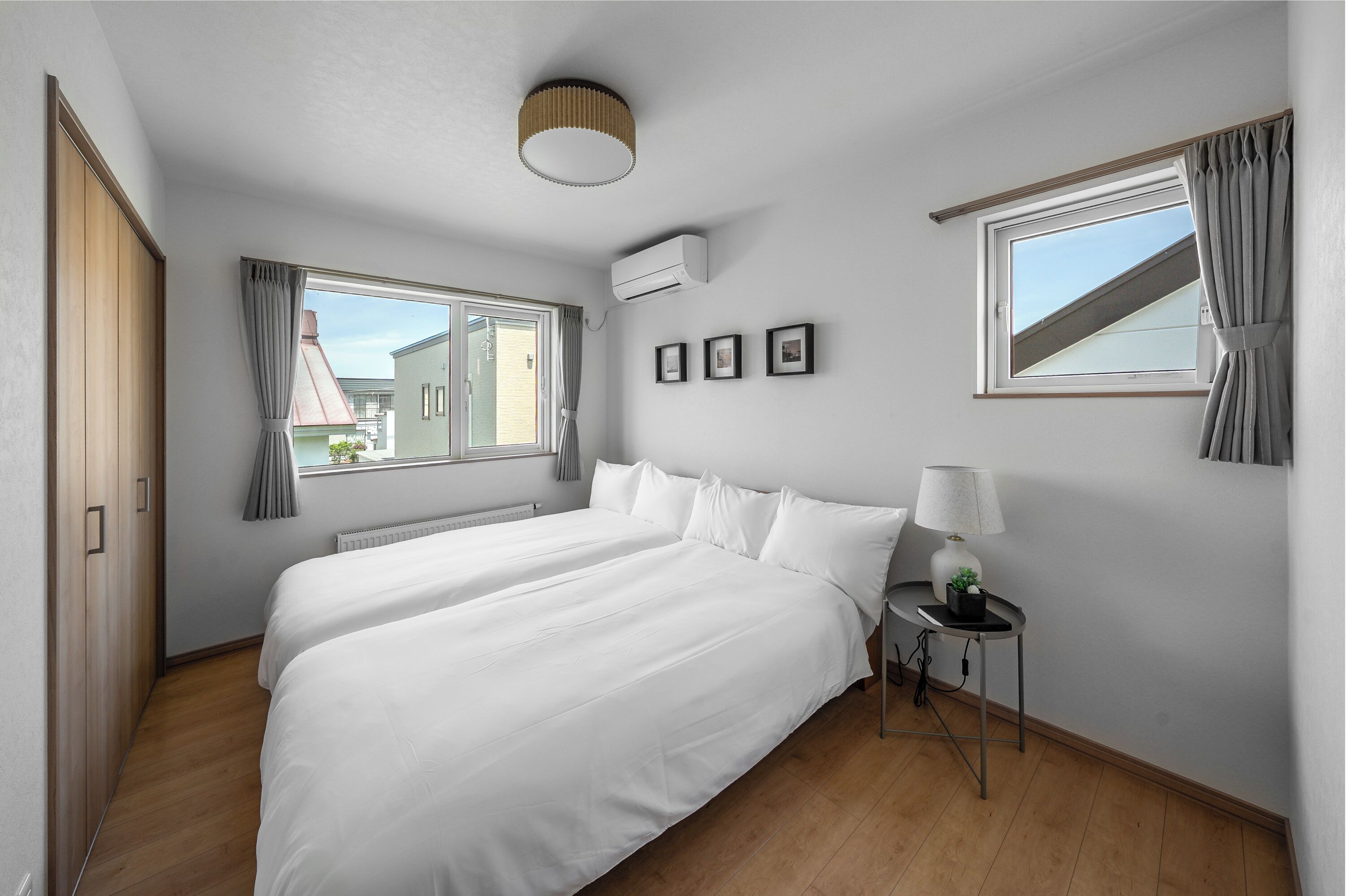 Une chambre d’hôtel avec deux lits, une petite table avec une lampe, une fenêtre avec des rideaux et un appareil de climatisation.