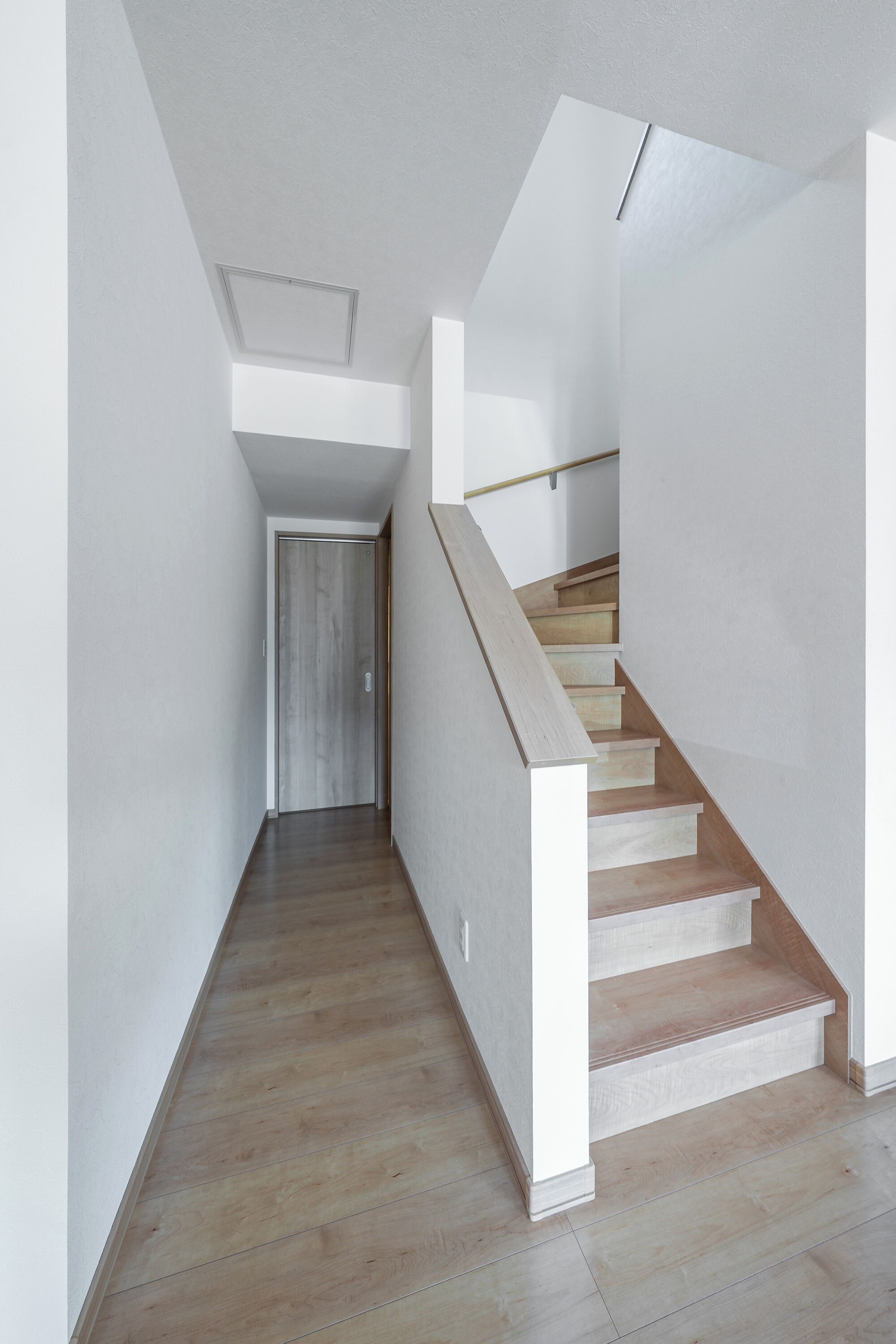A modern staircase with wooden steps and white walls.