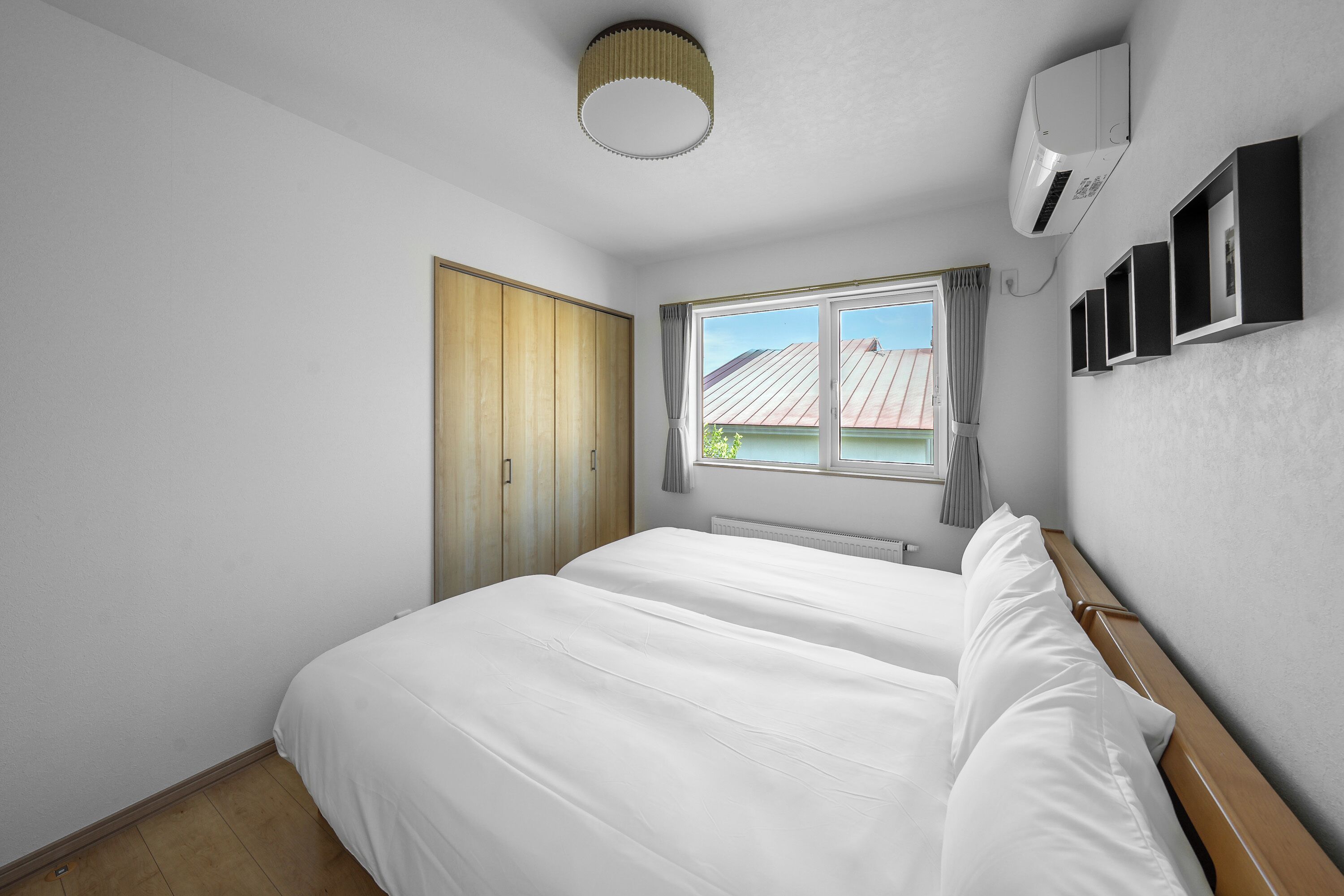 Un dormitorio con una cama grande, una ventana con cortinas, un ventilador de techo y aire acondicionado de pared.