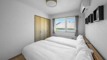 Un dormitorio con una cama grande, una ventana con cortinas, un ventilador de techo y aire acondicionado de pared.