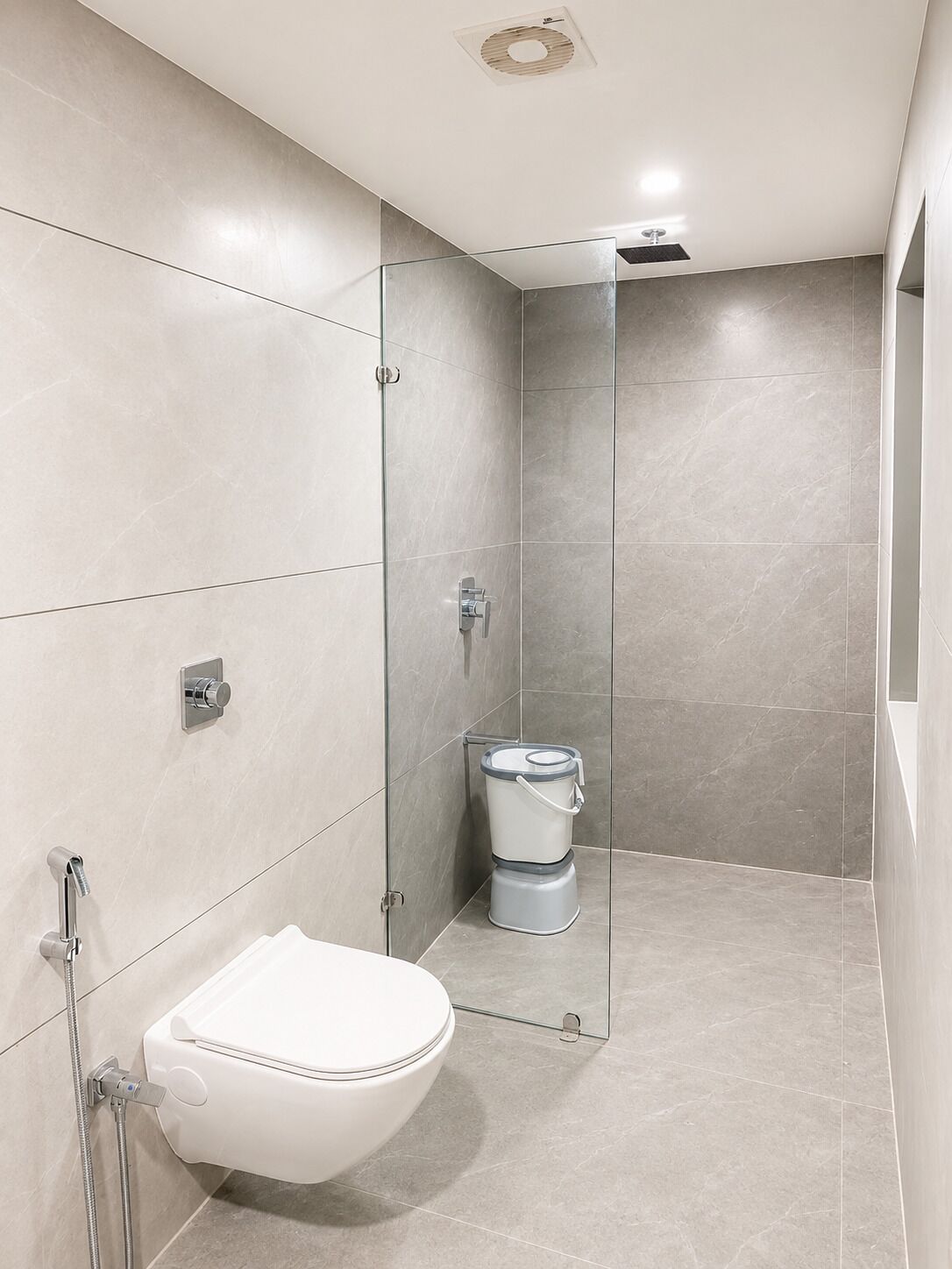A modern bathroom with a glass shower enclosure, a toilet, and a sink.