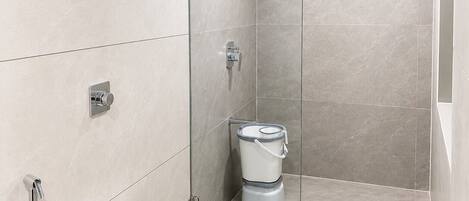A modern bathroom with a glass shower enclosure, a toilet, and a sink.