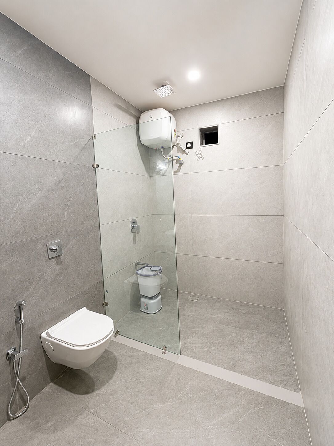 Un baño moderno con ducha envuelta en vidrio, inodoro blanco y ducha de mano.
