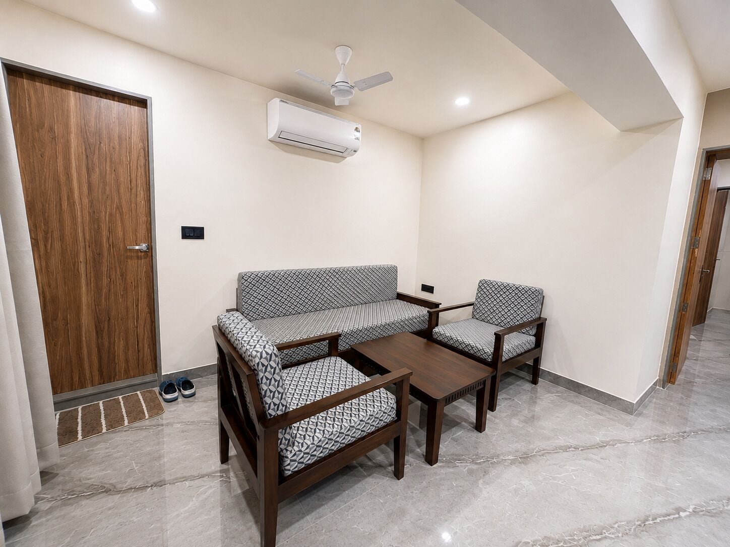 Una habitación con sofá, dos sillones, una mesa de centro, ventilador de techo y aire acondicionado.