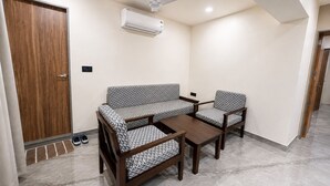 Ein Zimmer mit einer Couch, zwei Sesseln, einem Couchtisch, einem Deckenventilator und einer Klimaanlage.