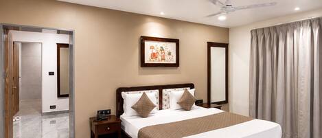 A hotel room with a large bed, a ceiling fan, a nightstand, and a framed picture on the wall.