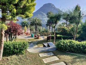 A landscaped garden with a paved pathway, palm trees, and a mountain in the background. - Grand Valley - A boutique Resort in Mount Abu (Mount Abu)