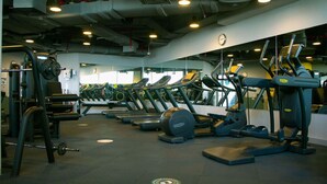A gym with multiple treadmills, weight machines, and a clock on the wall.