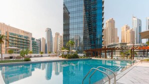 Una piscina con un paisaje urbano de fondo, rodeada de palmeras y edificios modernos.