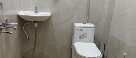 A small bathroom with a white sink, toilet, and a mirror on the wall.