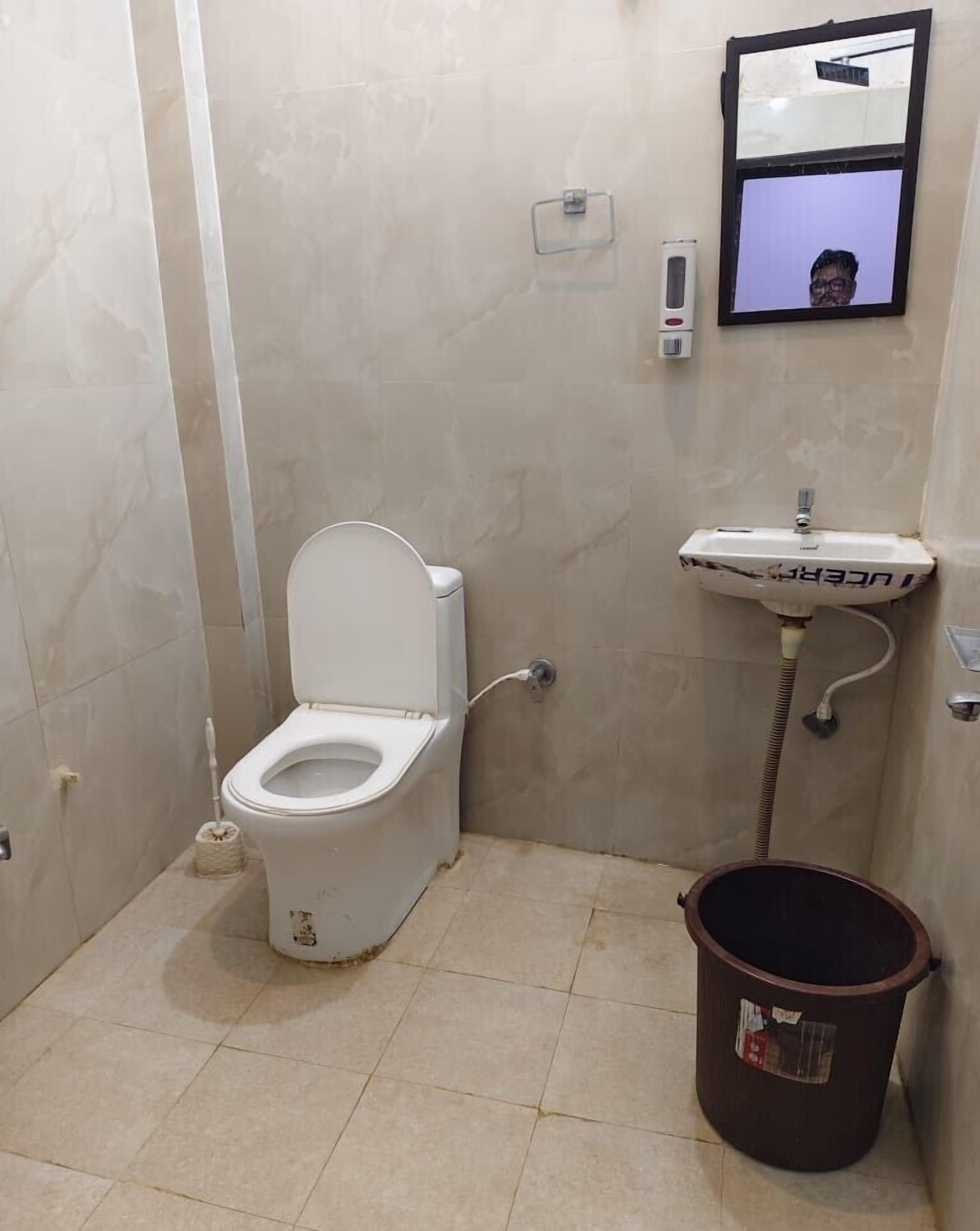 A small bathroom with a toilet, a sink, and a bucket.