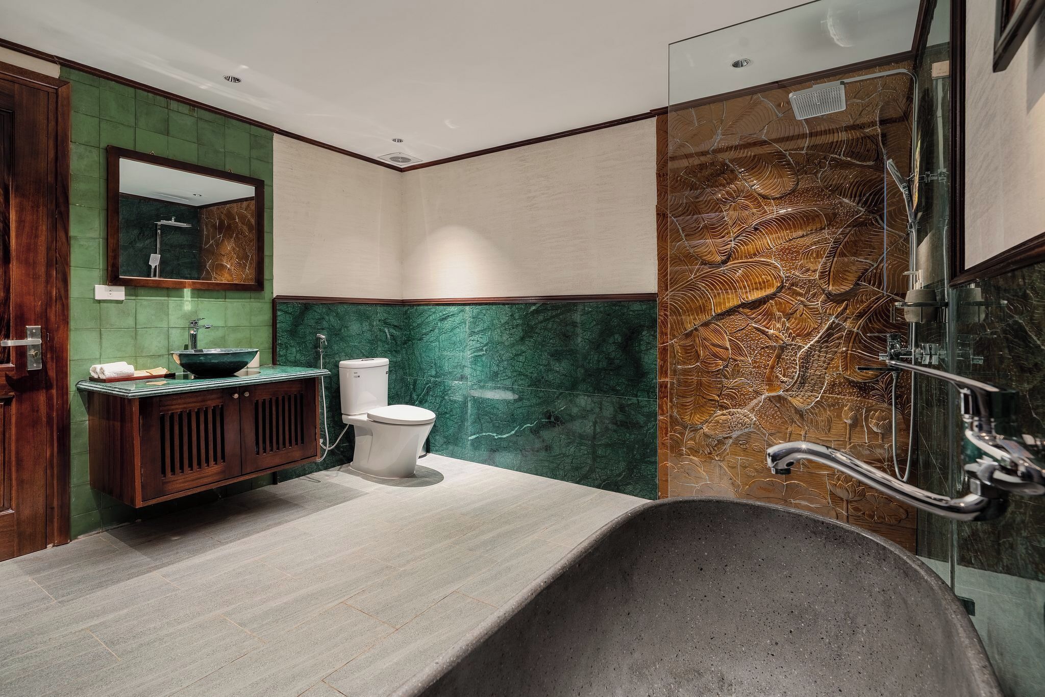 A modern bathroom with a freestanding bathtub, a wooden vanity, a toilet, and a large mirror.