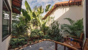 A courtyard with a stone floor, wooden chairs, and tropical plants. - The Greenary Garden (Ninh Binh)