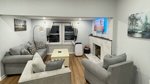 A modern living room with grey sofas, a coffee table, a TV, and a fireplace. - Charming Lakeview, 3 Bedroom home in Colchester (Colchester)